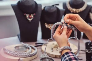 A person crafts a necklace from braided material.