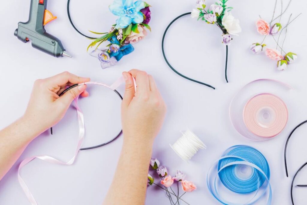 A person crafting a floral headband using ribbons.