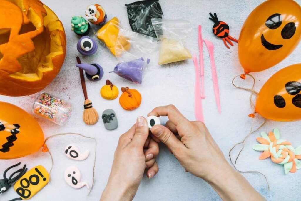 A person's hands crafting Halloween decorations with pumpkins.